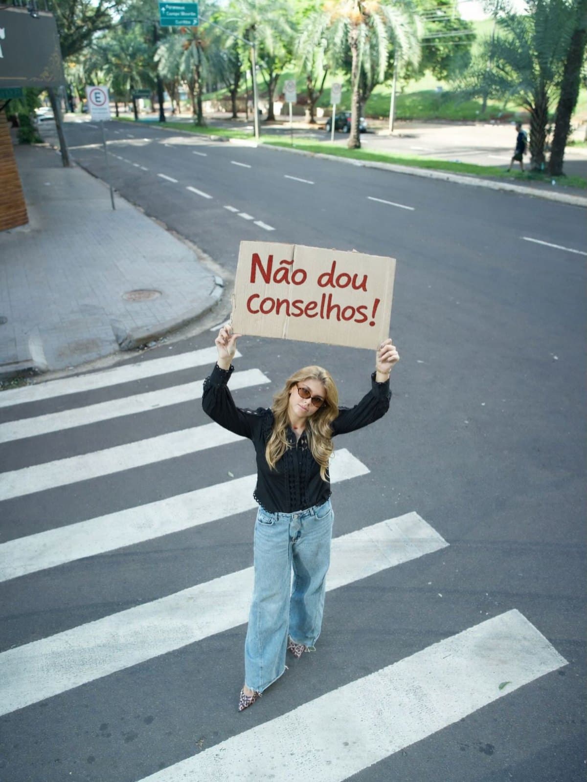 Ana Luiza na faixa de pedestres segurando um cartaz escrito “Não dou conselhos!”
